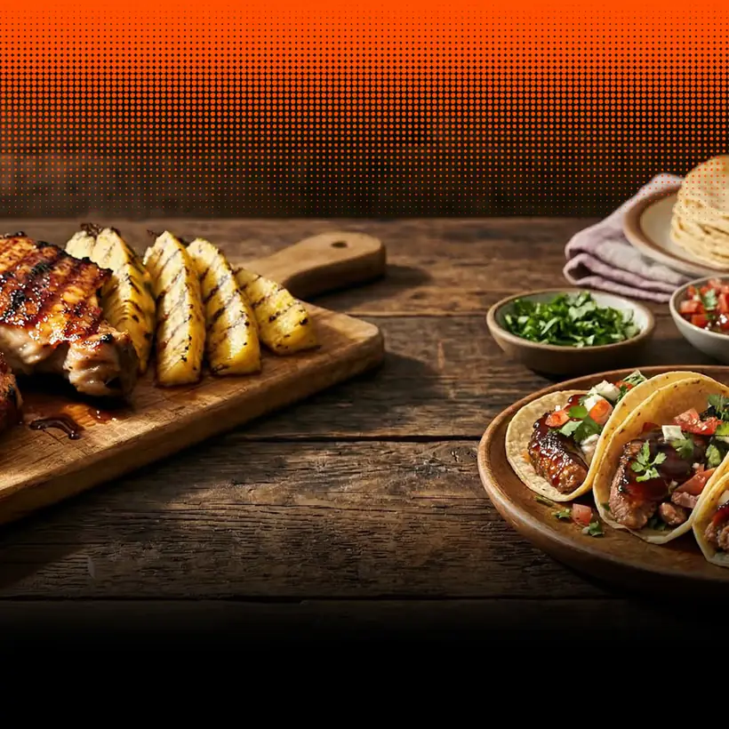 Churrasco y piña a la parrilla en una tabla de madera, con tacos y tortillas al lado.